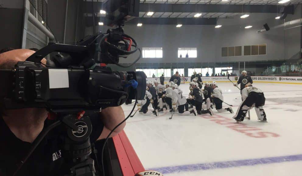 Professional video cameraman from Levy Production Group filming hockey team on ice