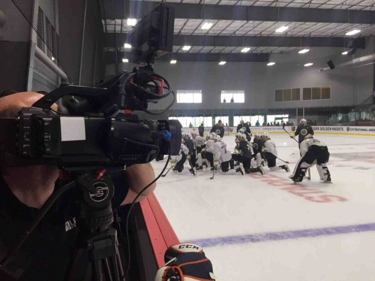 Professional video cameraman from Levy Production Group filming hockey team on ice