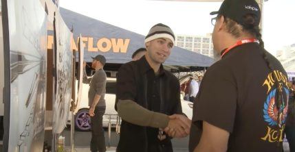 Young man wearing beanie shaking hands with man wearing a hat with a pony tail