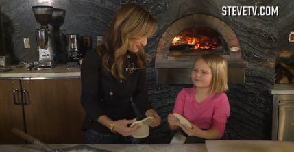 Giada DeLaurentiss holding dough and talking to young girl in front of wood-fired oven