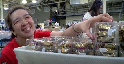 Woman smiling and reaching for box of candy at Opportunity Village